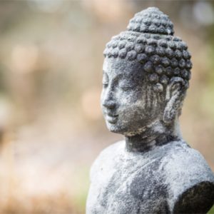stone buddha with eyes closed sitting outside